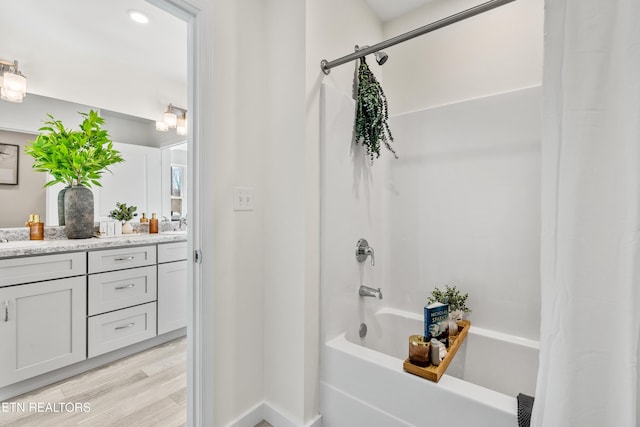 bathroom with double vanity, shower / bathtub combination with curtain, wood finished floors, and a sink