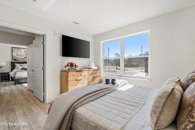 bedroom with light wood-type flooring and visible vents