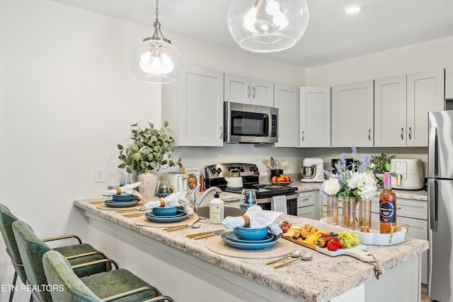 kitchen featuring decorative light fixtures, stainless steel appliances, a breakfast bar, and light countertops