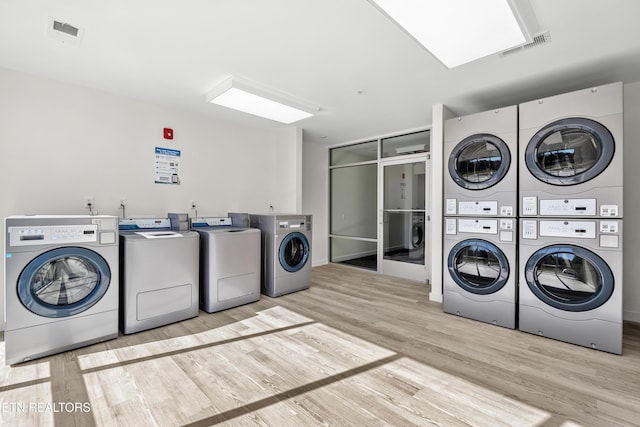 shared laundry area featuring washer and dryer, visible vents, wood finished floors, and stacked washer / dryer