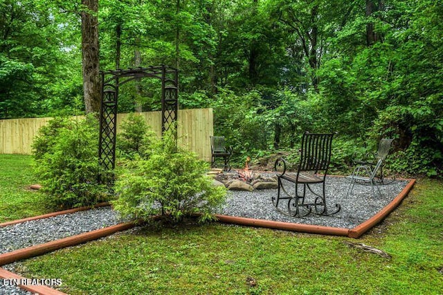 view of yard featuring a patio, an outdoor fire pit, and fence