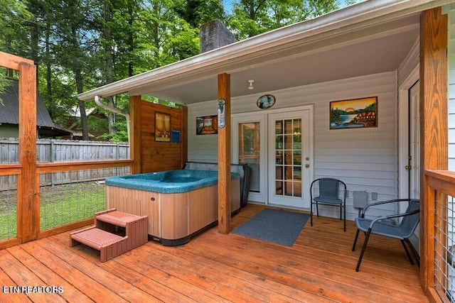 wooden terrace featuring a hot tub, fence, and french doors