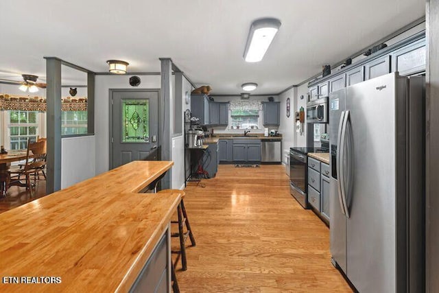 kitchen featuring light wood-style flooring, appliances with stainless steel finishes, gray cabinets, and a wealth of natural light