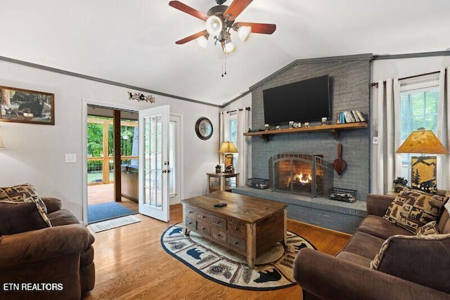 living room featuring vaulted ceiling, ornamental molding, wood finished floors, and a wealth of natural light