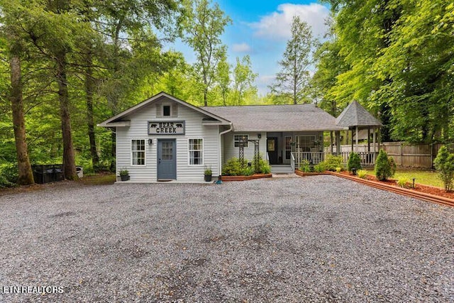 view of front of house with driveway, fence, and a porch