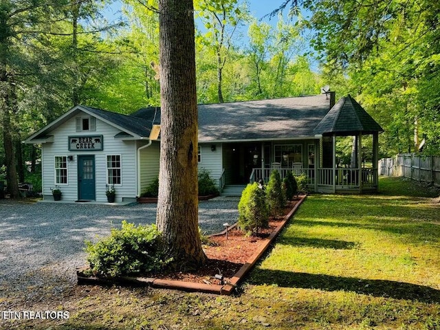 view of front of property with a porch, a front lawn, and fence