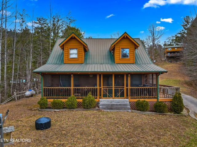 view of front facade with a sunroom, faux log siding, and metal roof