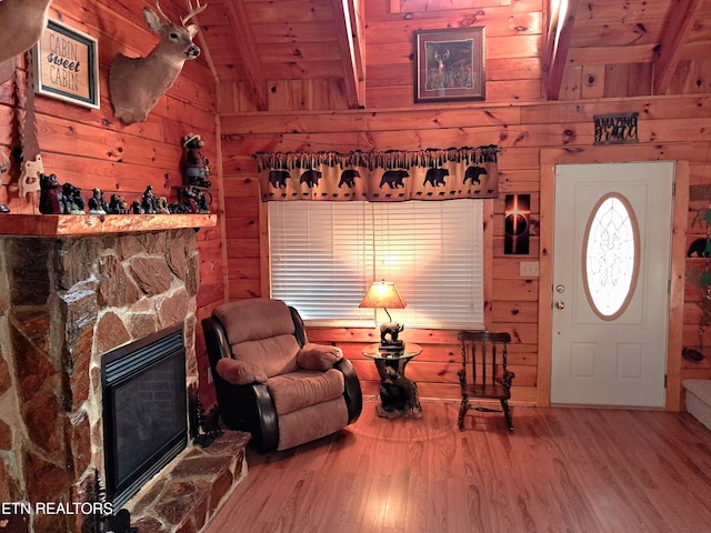 interior space featuring lofted ceiling with beams, wood walls, a fireplace, wood finished floors, and wood ceiling