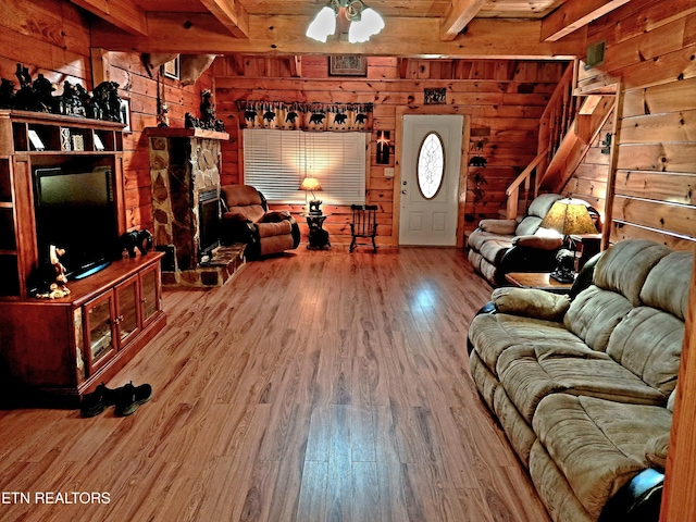 living room with wood walls, stairs, beam ceiling, and wood finished floors