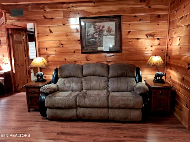 living area featuring wood walls, wood finished floors, and visible vents