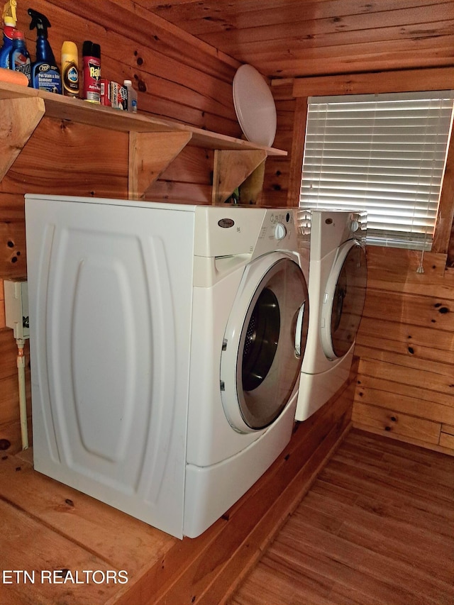 washroom featuring wood walls, laundry area, separate washer and dryer, and wood finished floors