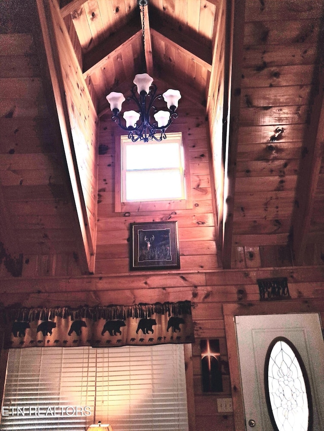 interior space with vaulted ceiling with beams, wooden ceiling, a notable chandelier, and wooden walls