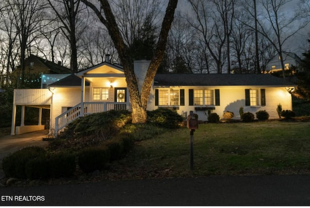 ranch-style house with driveway, a carport, and a front yard