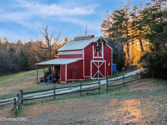 view of barn featuring a lawn and fence