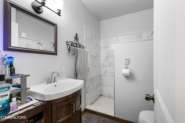 full bath featuring toilet, a tile shower, and vanity