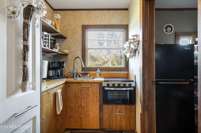 kitchen with brown cabinets, freestanding refrigerator, light countertops, open shelves, and a sink