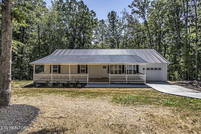 view of front facade with a garage, covered porch, metal roof, and driveway