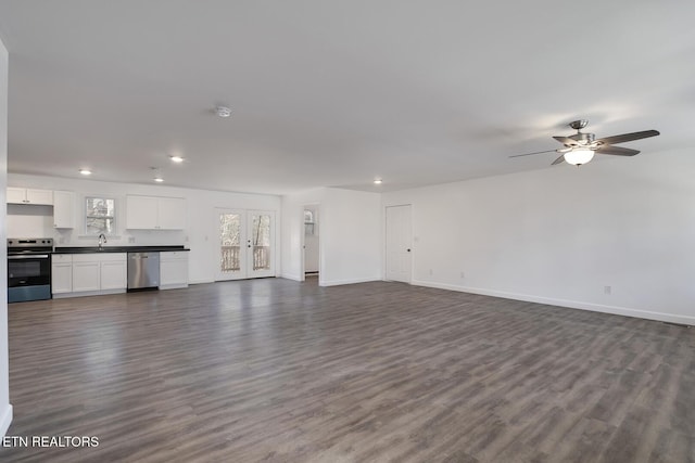 unfurnished living room featuring dark wood-type flooring, recessed lighting, a sink, and baseboards