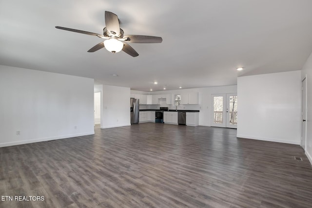 unfurnished living room with ceiling fan, dark wood-style flooring, a sink, and baseboards