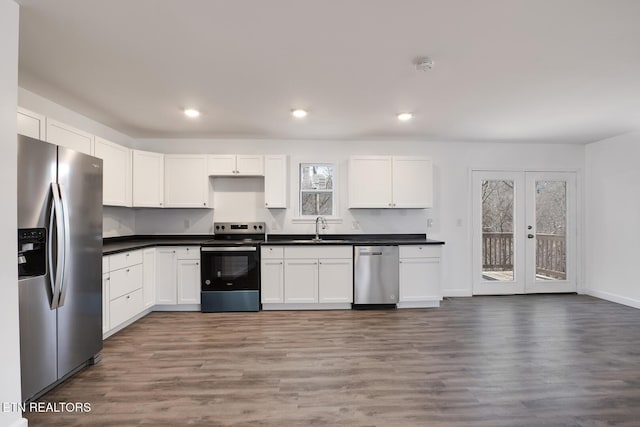 kitchen featuring stainless steel appliances, wood finished floors, dark countertops, and a sink