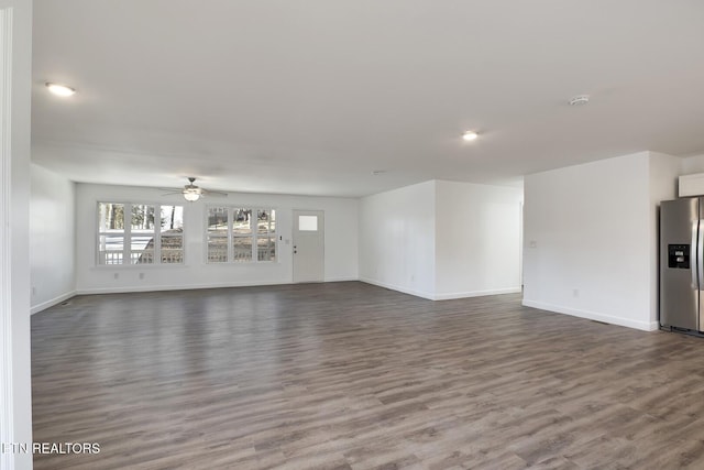 unfurnished living room with ceiling fan, dark wood-type flooring, and baseboards