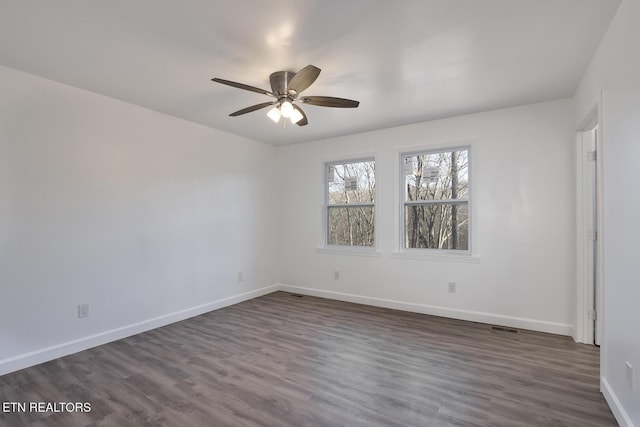 empty room with dark wood-style floors, ceiling fan, and baseboards