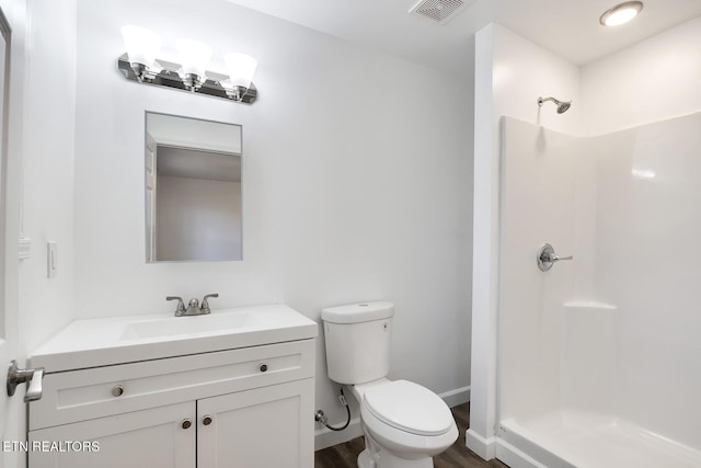 bathroom with toilet, vanity, visible vents, baseboards, and a stall shower