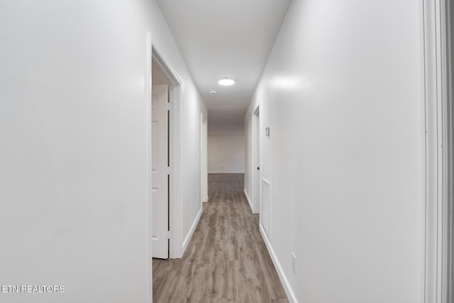 hall featuring light wood-type flooring and baseboards