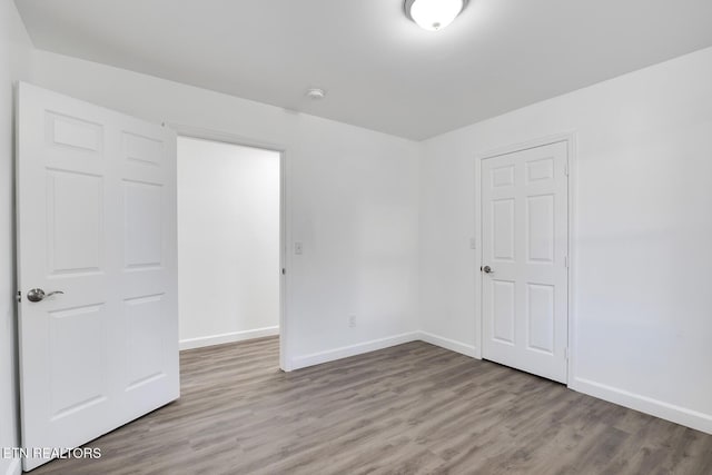 spare room with baseboards and wood finished floors