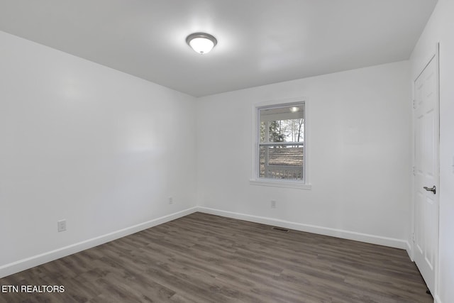 unfurnished room with visible vents, baseboards, and dark wood finished floors