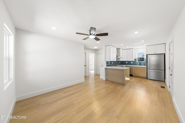 kitchen featuring decorative backsplash, appliances with stainless steel finishes, light countertops, light wood-style floors, and a sink