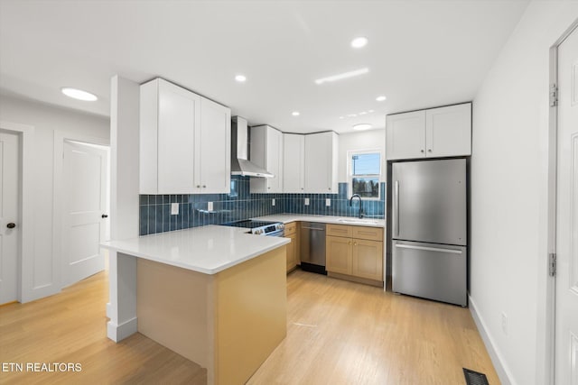 kitchen featuring stainless steel appliances, a sink, visible vents, decorative backsplash, and wall chimney exhaust hood