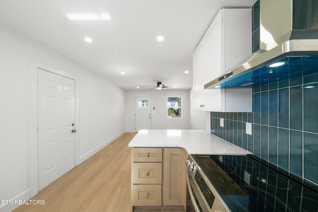 kitchen with recessed lighting, wall chimney range hood, light wood-type flooring, stainless steel electric stove, and tasteful backsplash