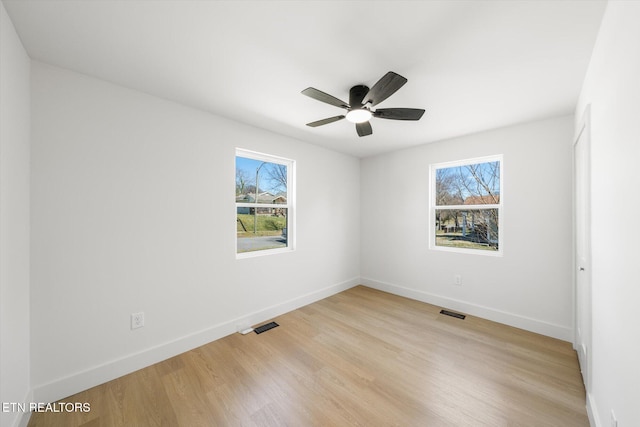 unfurnished room featuring light wood-style floors, visible vents, baseboards, and a ceiling fan