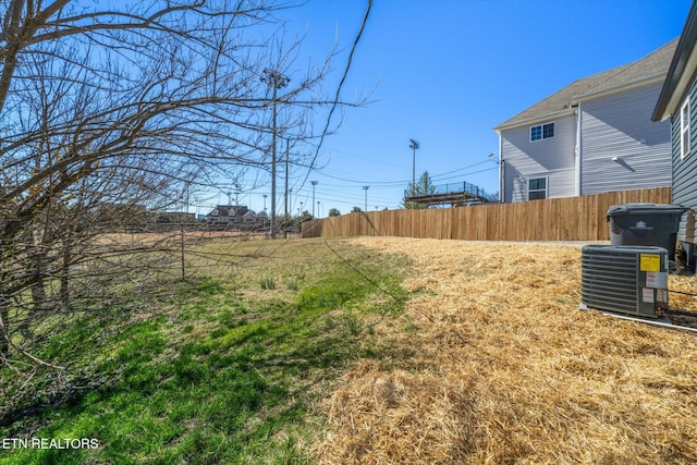 view of yard featuring central AC and fence