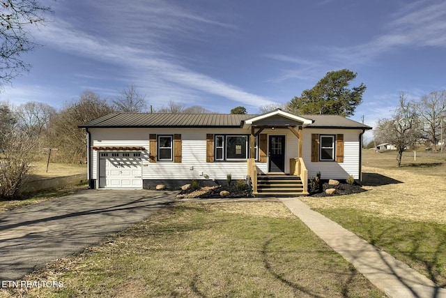 view of front of home featuring aphalt driveway, an attached garage, metal roof, and a front lawn