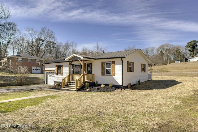 view of front of home with metal roof, a front lawn, an attached garage, and driveway