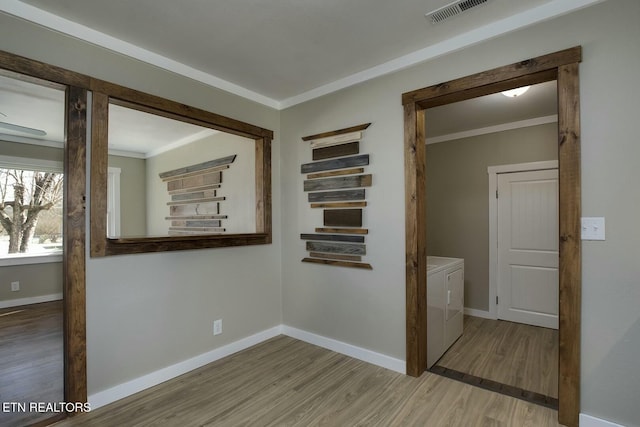 hall with visible vents, crown molding, baseboards, washer and clothes dryer, and wood finished floors