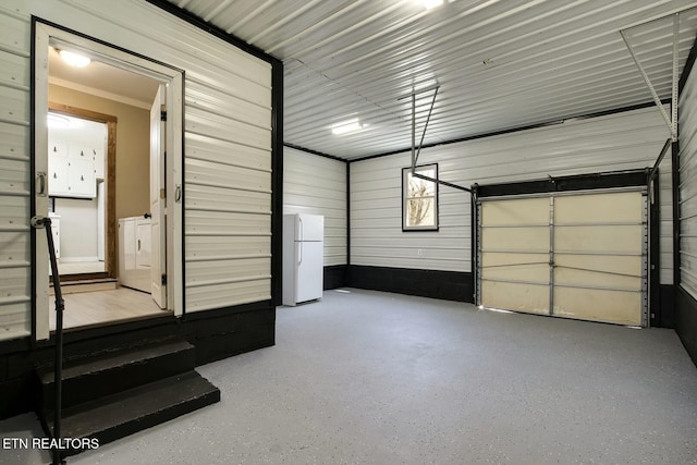 garage with washer / dryer, metal wall, and freestanding refrigerator