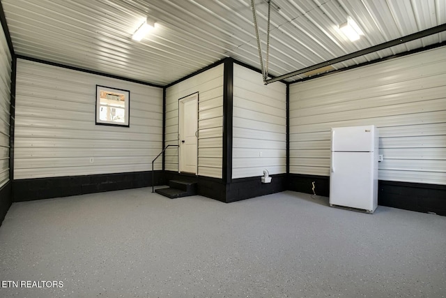 garage with metal wall and freestanding refrigerator