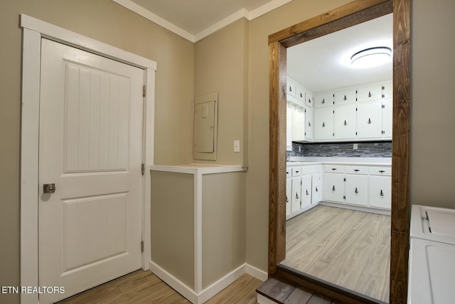 interior space with crown molding, baseboards, laundry area, light wood-style flooring, and washer / clothes dryer