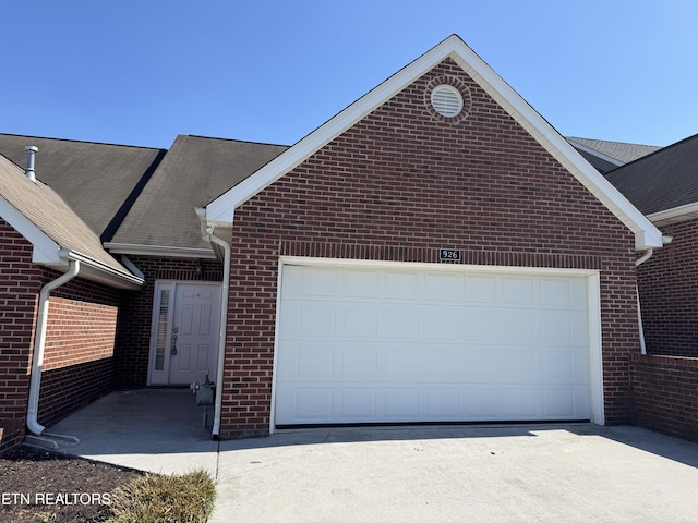 single story home with driveway, brick siding, and an attached garage