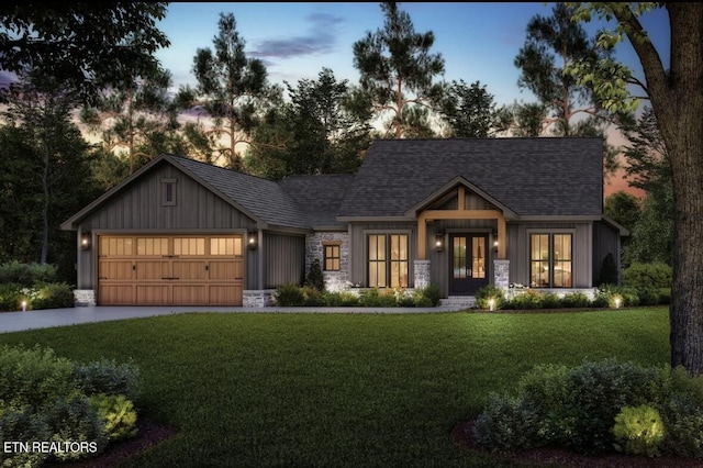 modern farmhouse style home with driveway, a garage, french doors, stone siding, and a yard