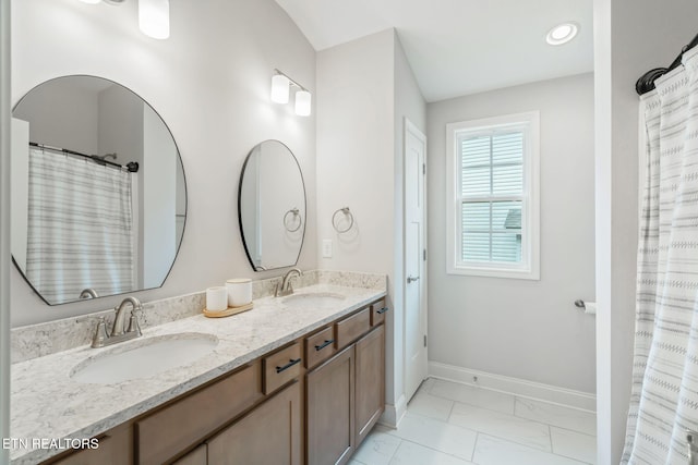 full bath with marble finish floor, a sink, baseboards, and double vanity