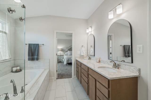 ensuite bathroom featuring double vanity, tiled bath, a sink, and ensuite bathroom