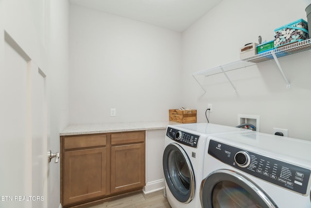 laundry area featuring cabinet space, light wood-style flooring, and separate washer and dryer