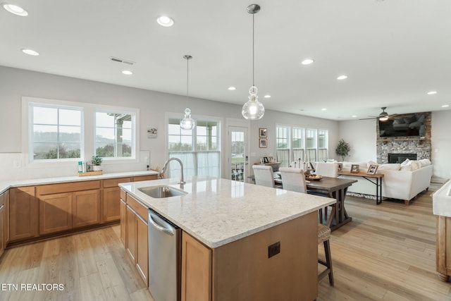 kitchen with light wood finished floors, stainless steel dishwasher, a sink, and visible vents