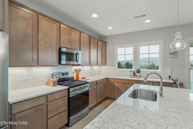 kitchen featuring stainless steel appliances, a sink, visible vents, and light stone countertops