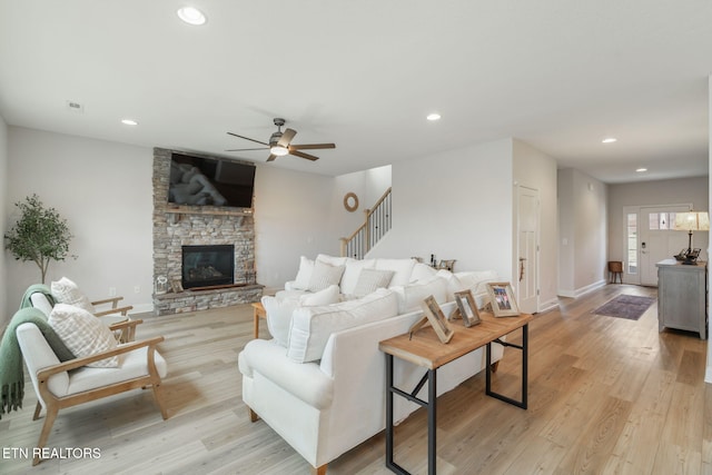 living room featuring light wood finished floors, a fireplace, stairway, and recessed lighting