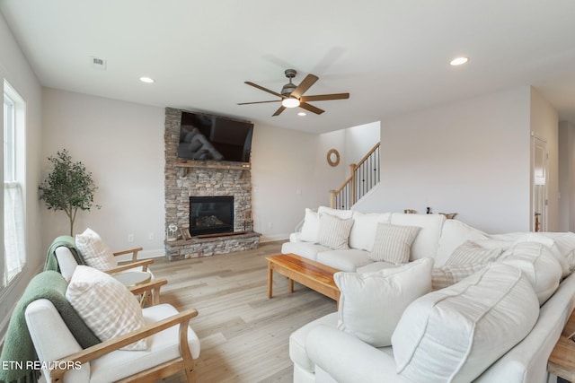 living area featuring recessed lighting, visible vents, light wood-style flooring, a stone fireplace, and baseboards